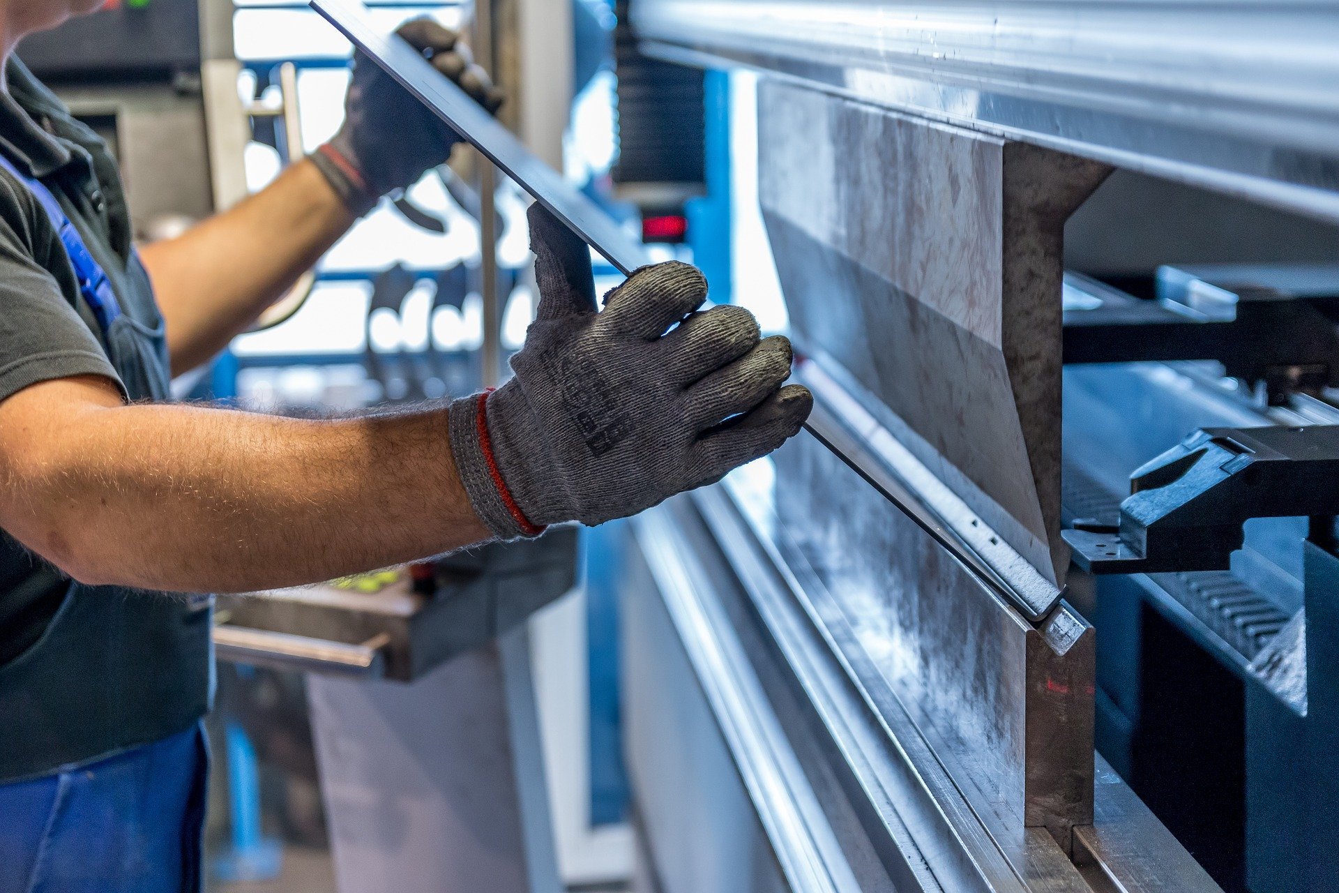 Mitarbeiter mit Schutzhandschuhen an einer Metallbearbeitungsmaschine